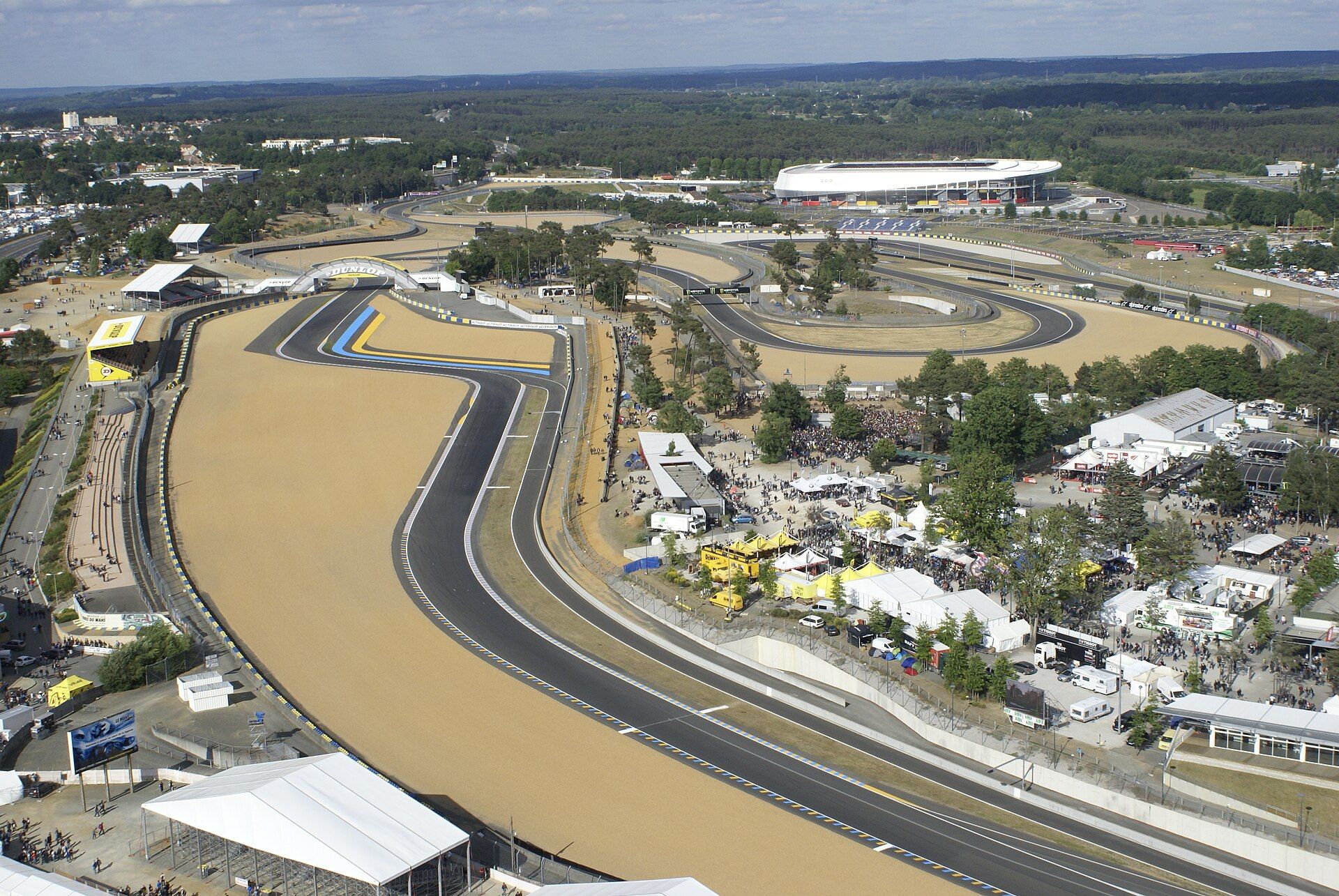 Zakręt, szykana i most Dunlop na torze Bugatti w Le Mans widziane z lotu ptaka, w tle stadion