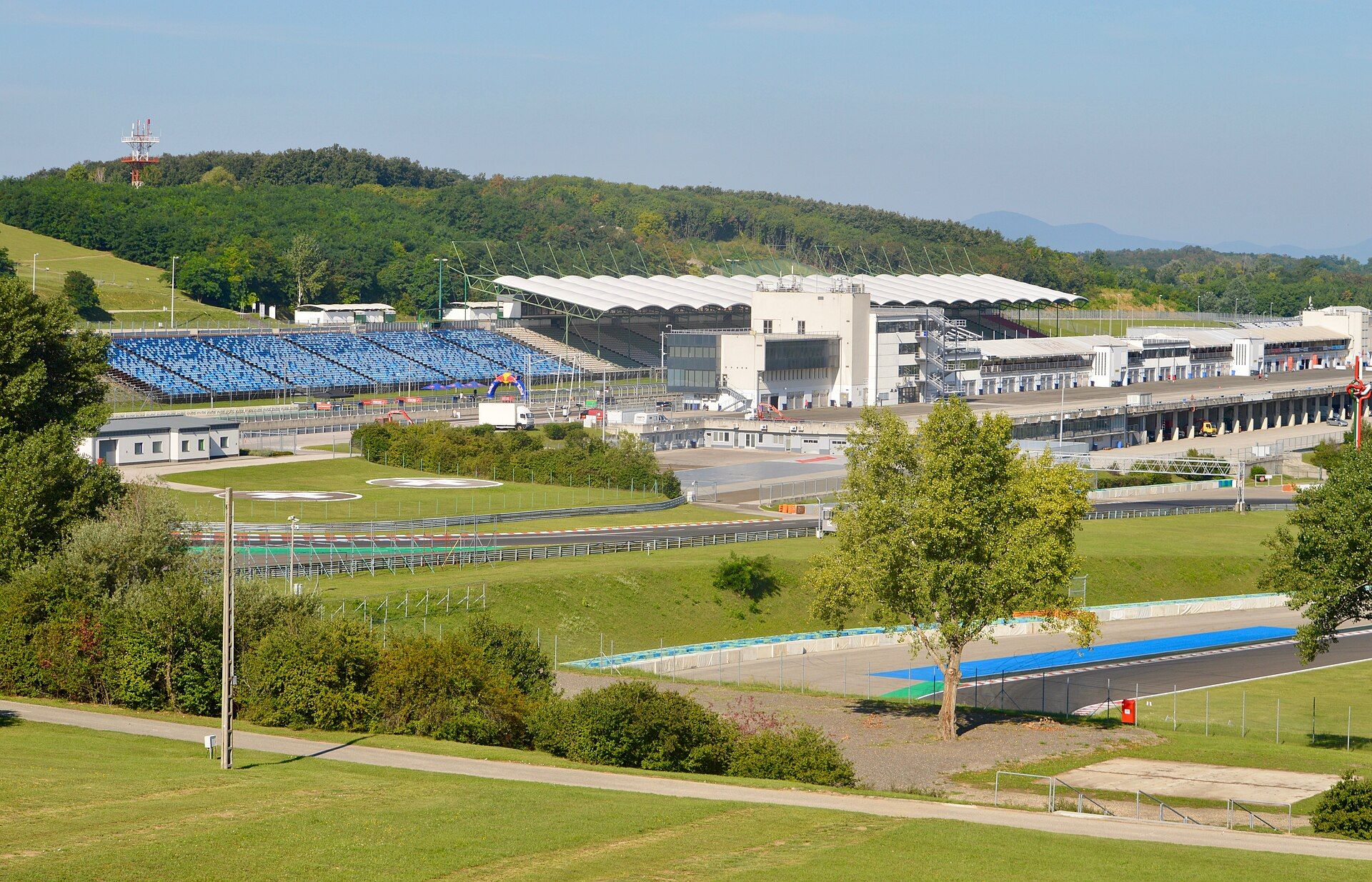 Trybuny i główne budynki toru Hungaroring widziane ze wzgórza, na pierwszym planie fragment nitki toru